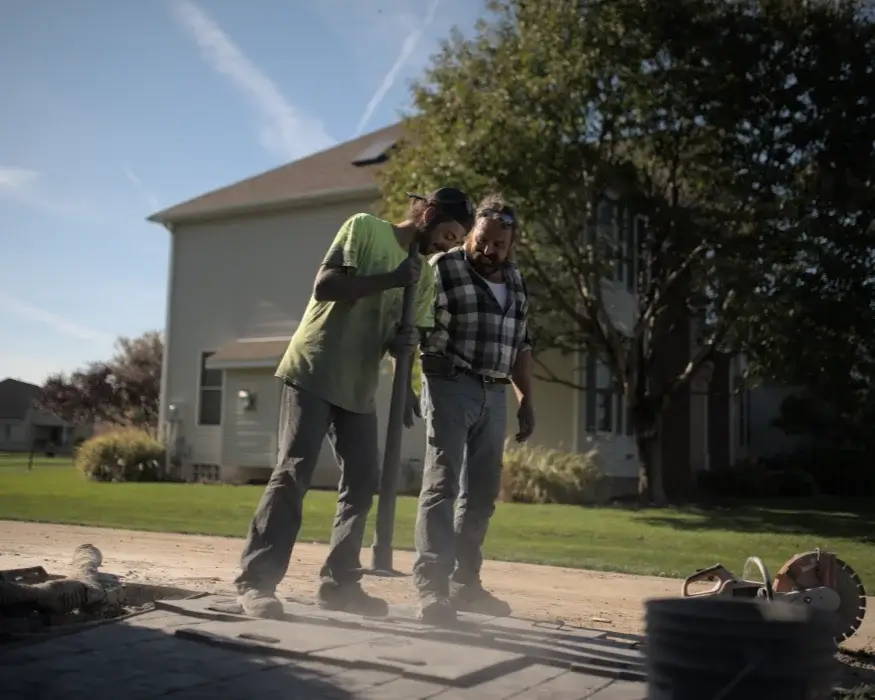 Two concrete workers working together to stamp concrete sidewalk