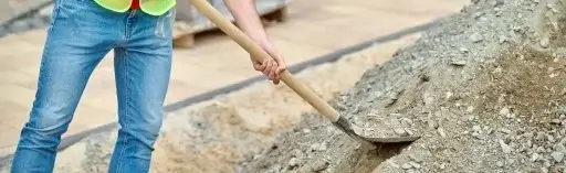 Concrete worker shoveling crushed stone aggregate